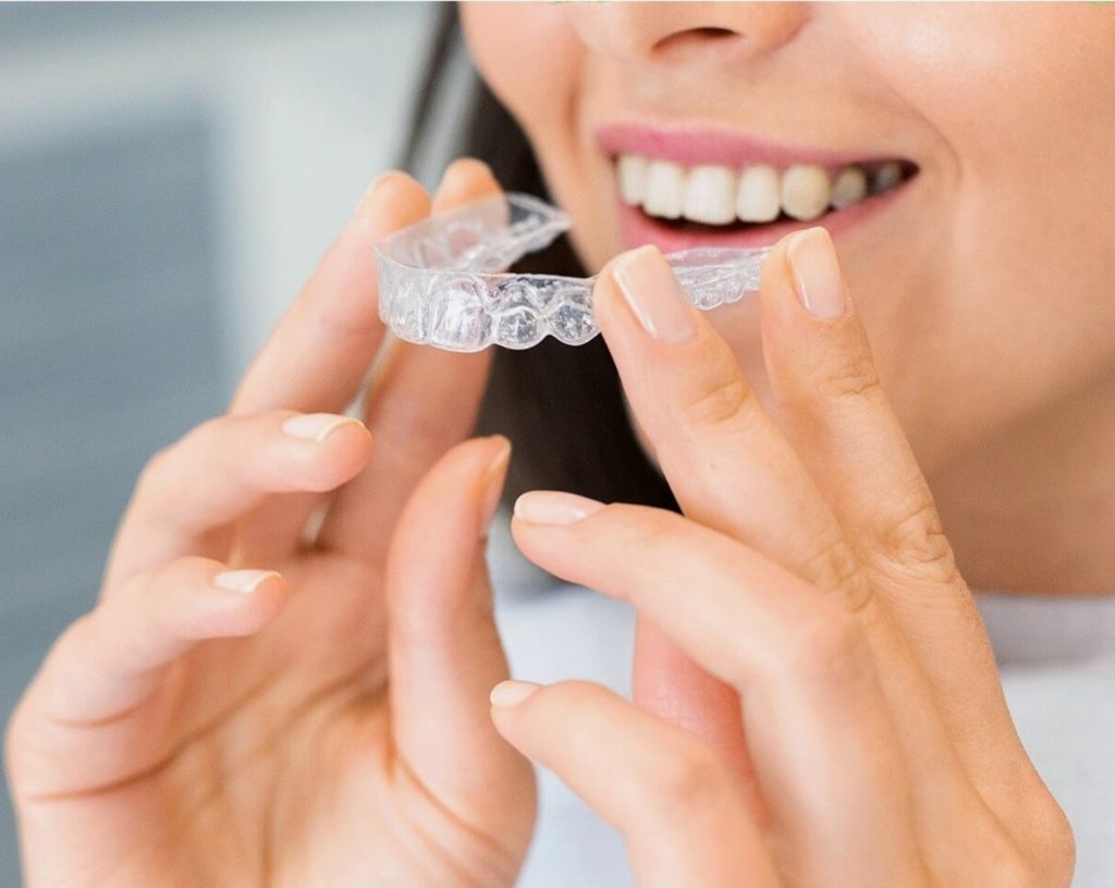 A woman holding an Invisalign aligner