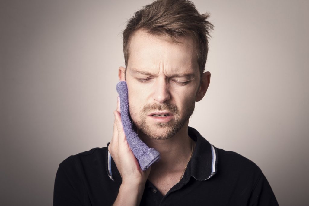 man with tooth pain holding his cheek