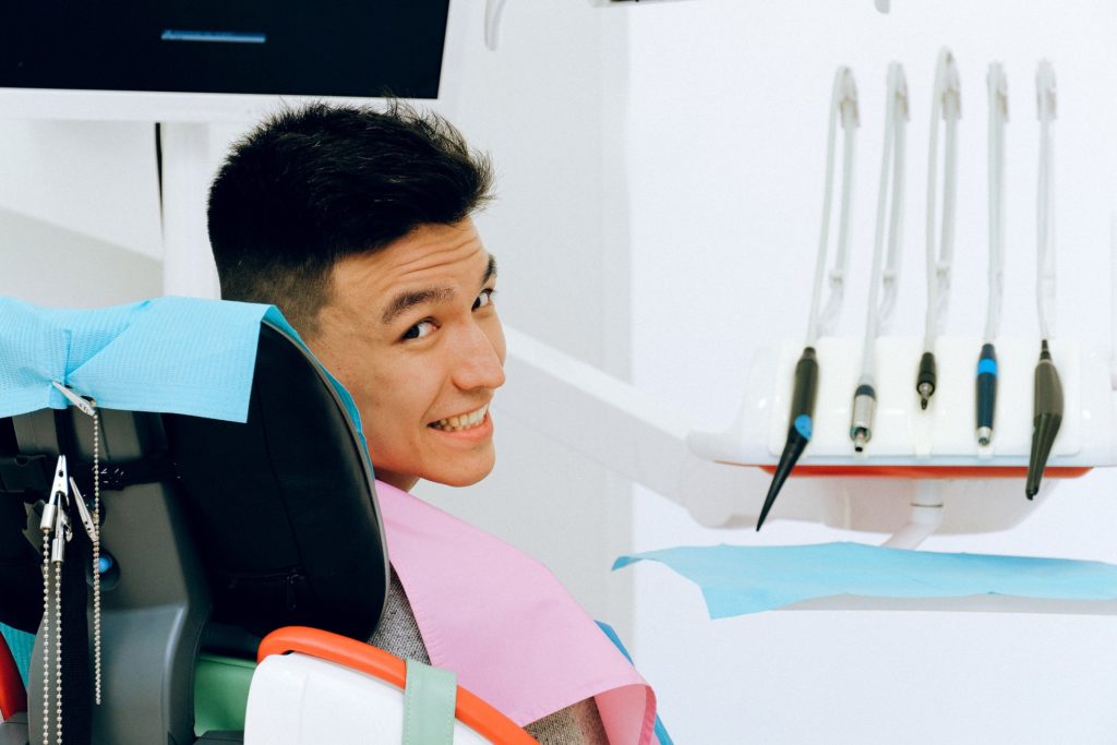 A smiling man sits in a dental chair after receiving implant retained dentures.