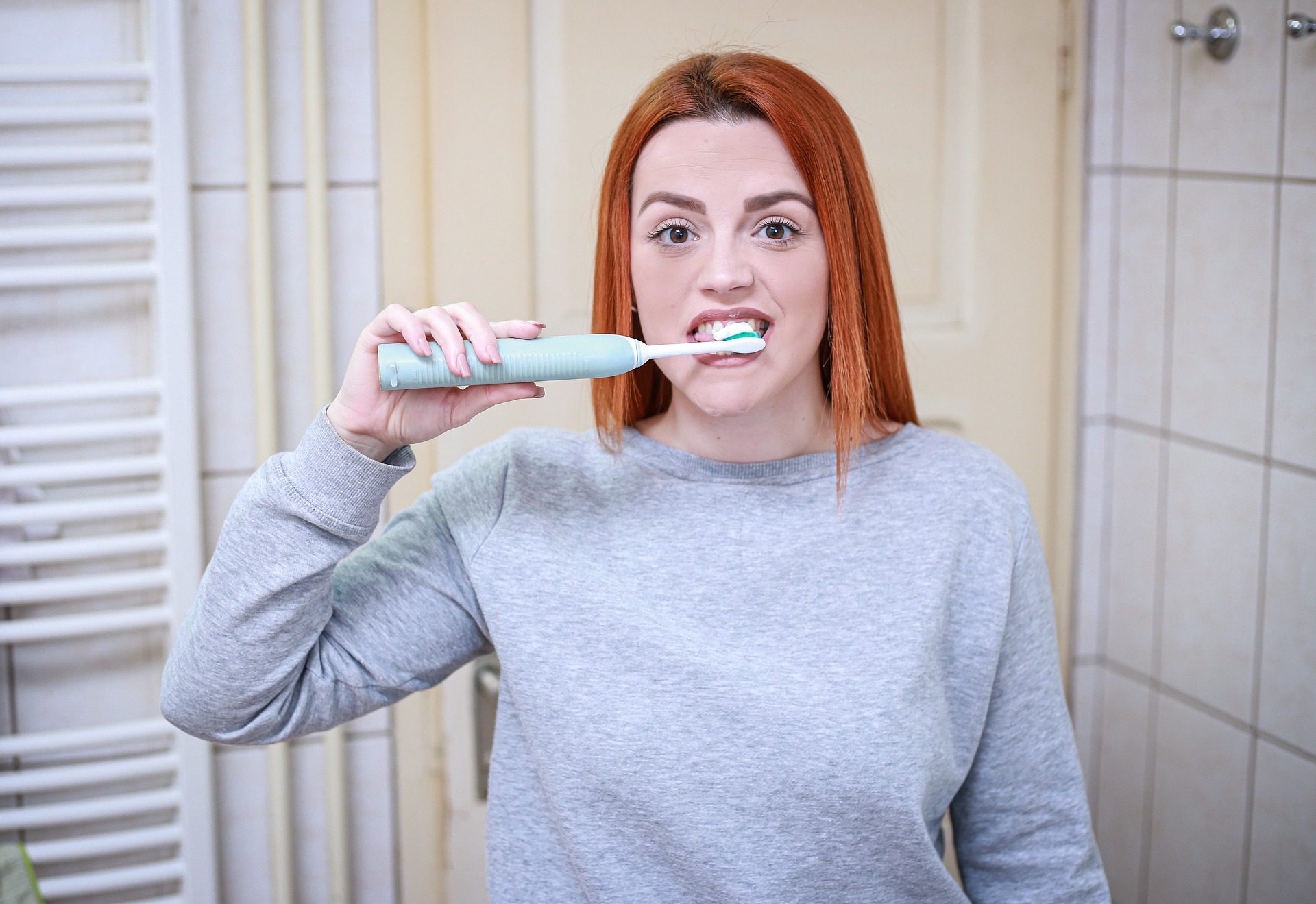 A woman brushing her teeth in the mirror at her new dentist in Norwalk.