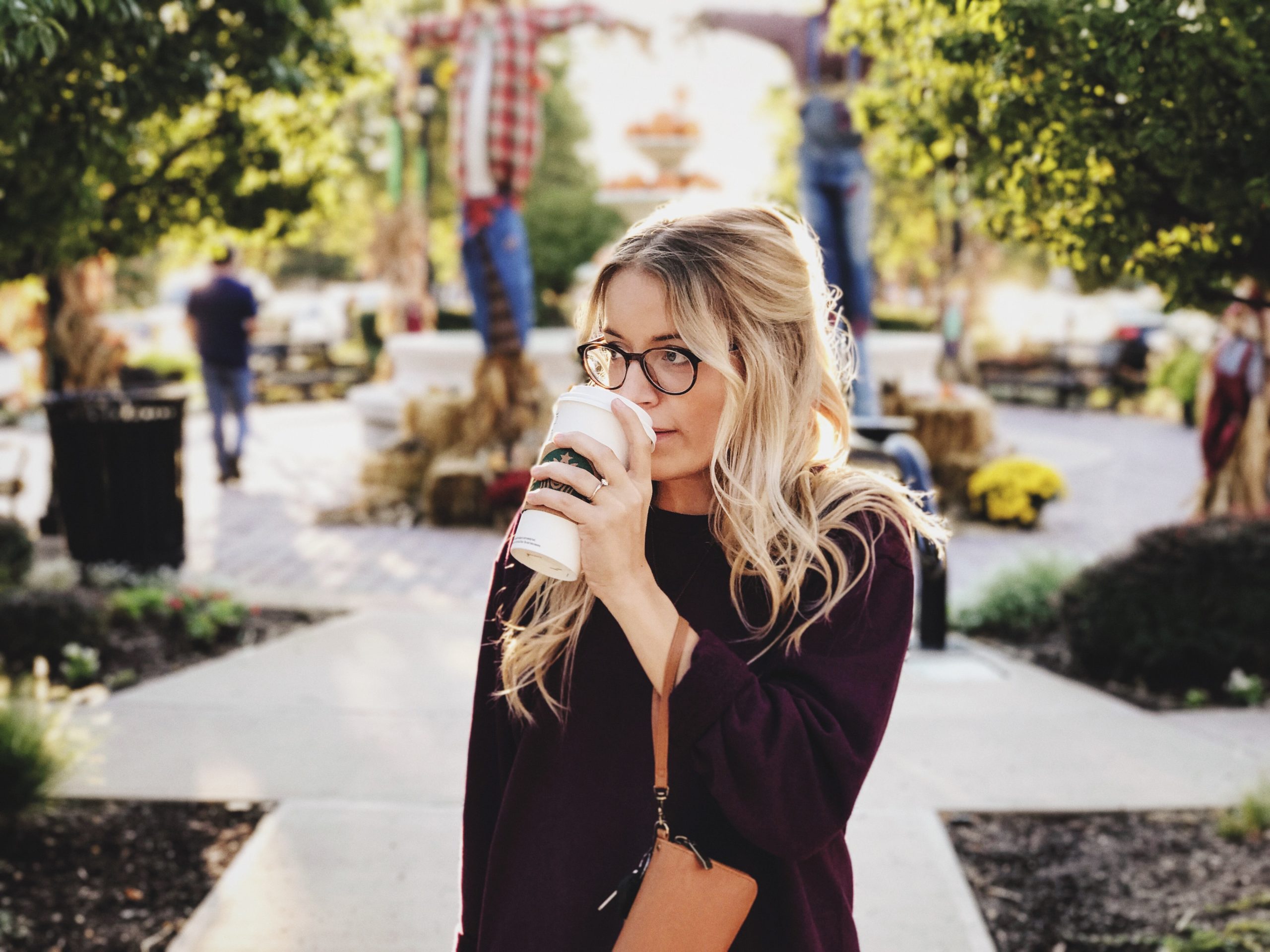 An anxious woman drinking coffee from a white cup in a courtyard