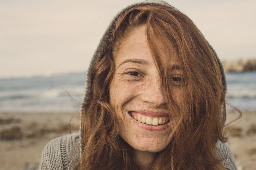 woman with freckles smiling near beach