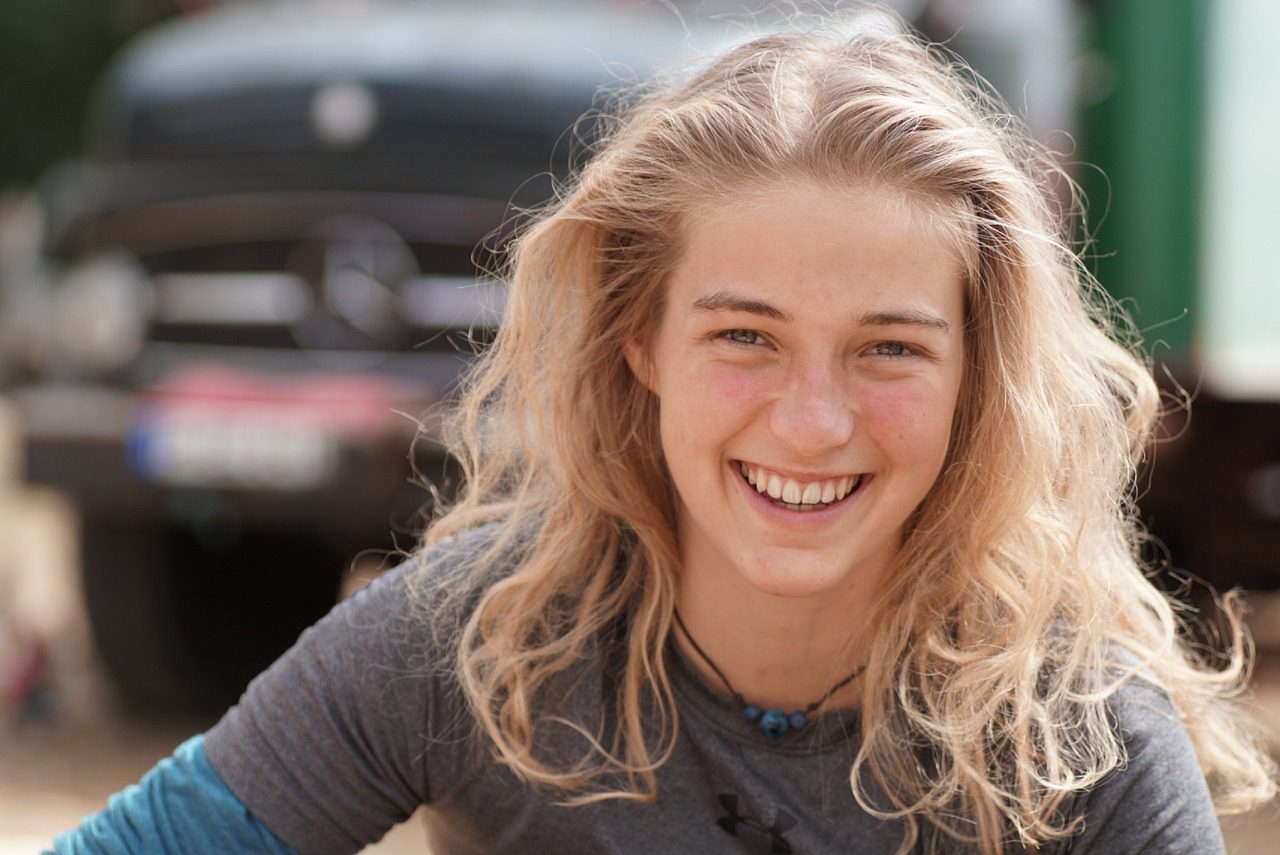 girl smiling with blonde hair and blurred background