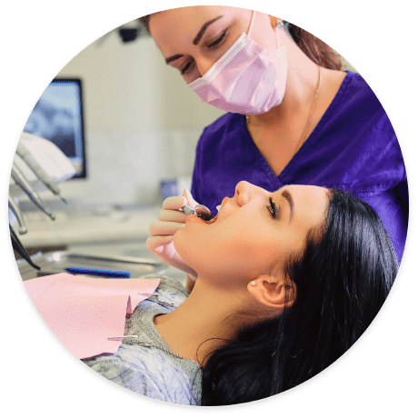 A Dentist from Norwalk, CA in purple looking at girl’s mouth