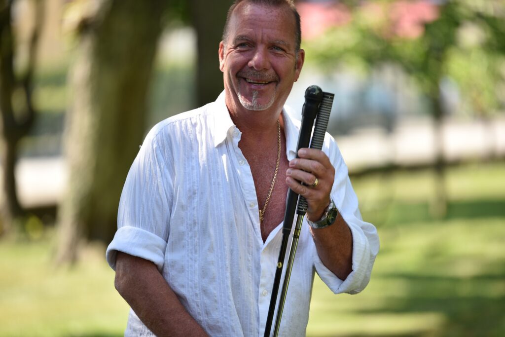 Man wearing dentures smiling with golf sticks