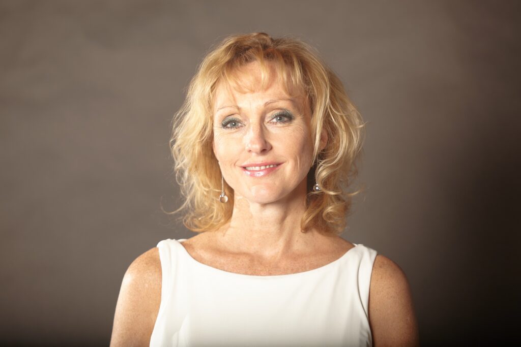 Woman wearing dentures smiling against brown background