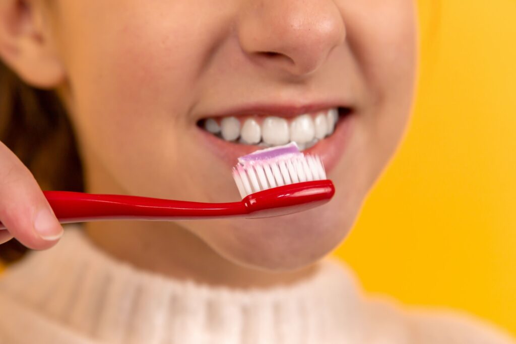 A teenage child holding a prepared toothbrush