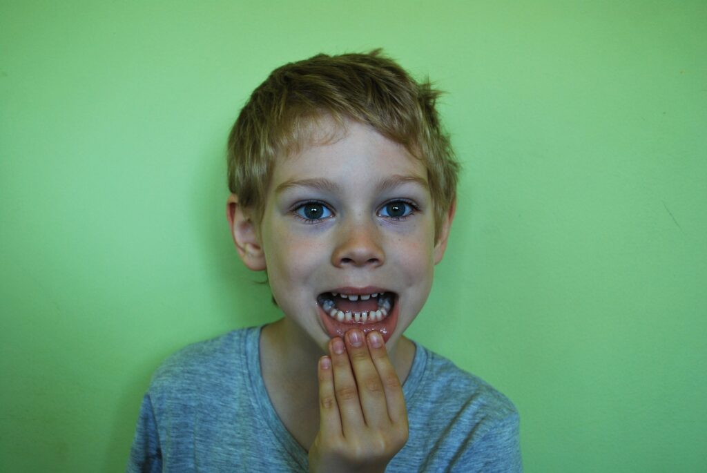 boy showing bottom teeth in front of green background