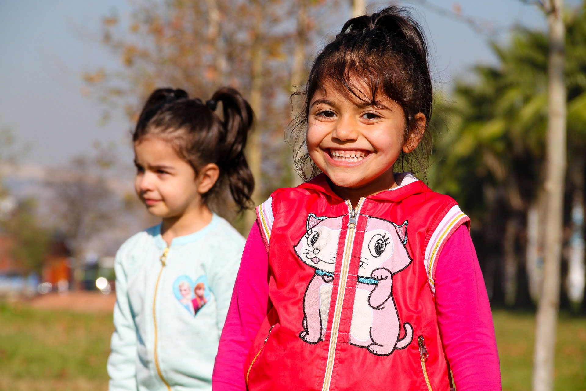 two girls with ponytails smiling outside