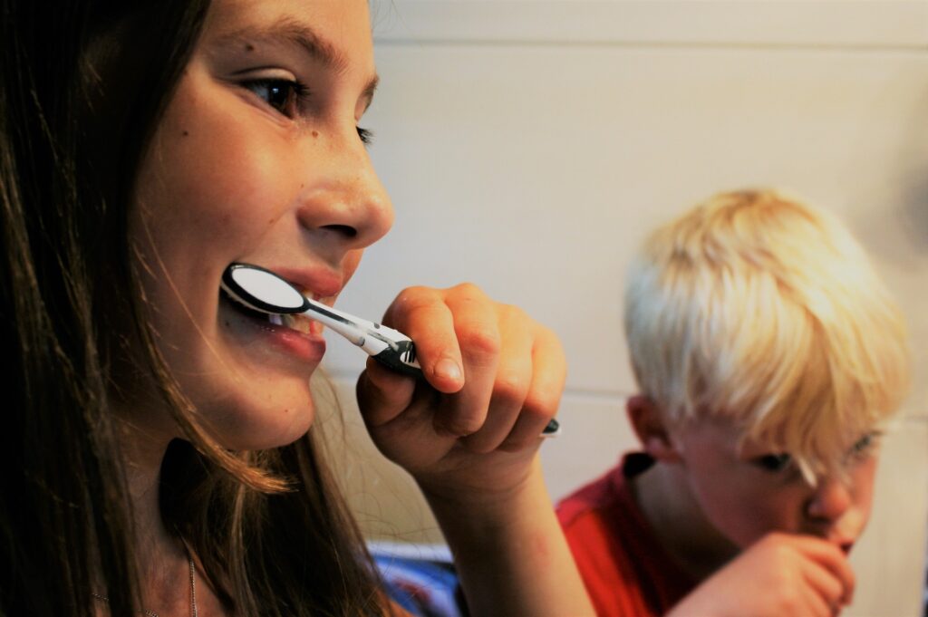 girl brushing teeth beside young boy
