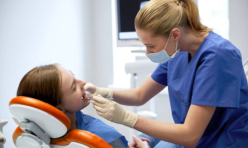 Dentist from Norwalk, CA looking in blue looking into girl’s mouth